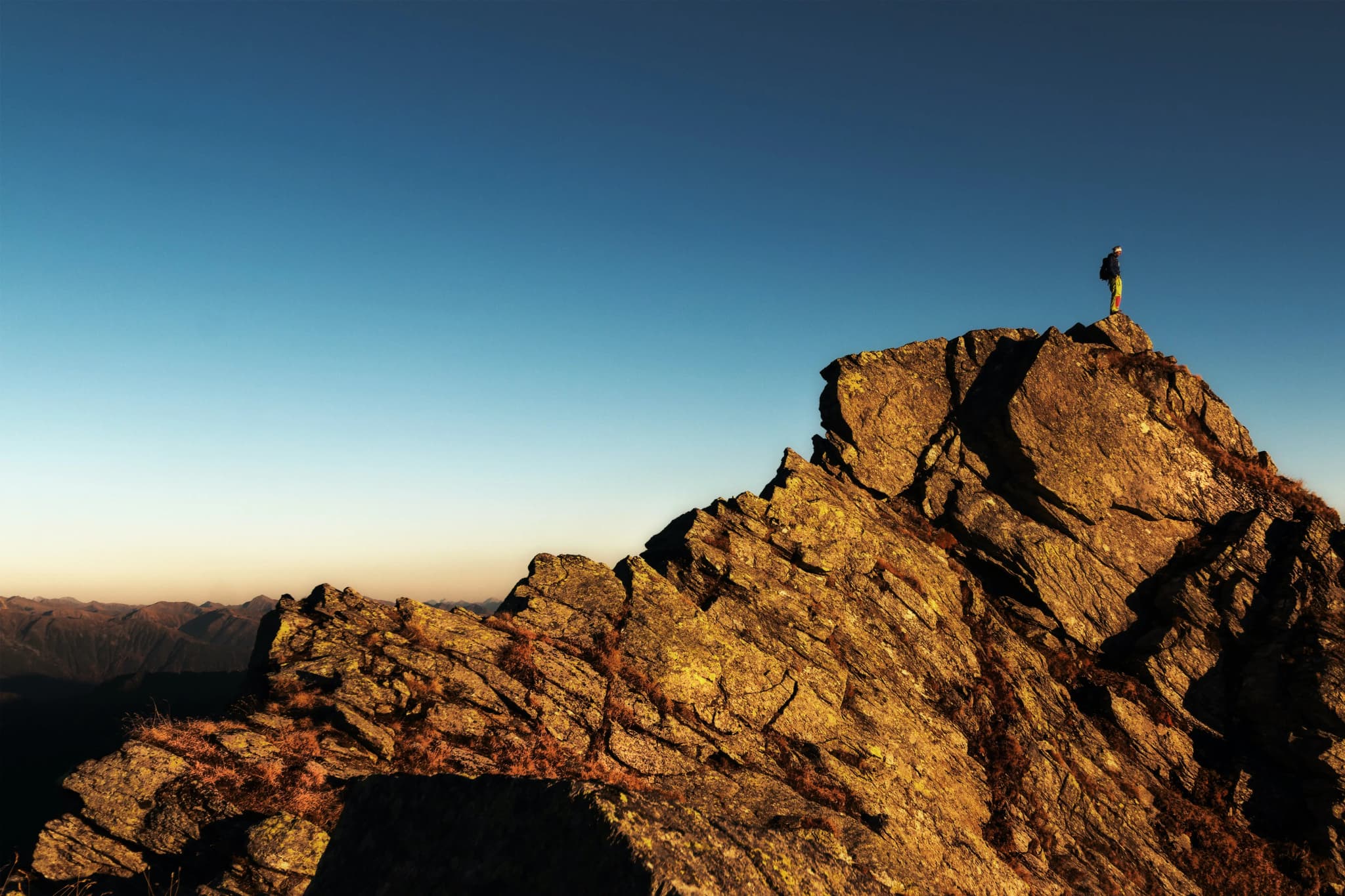 A landscape of mountains and a man standing on top.